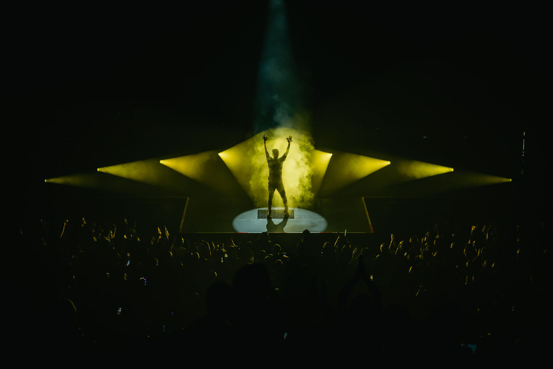A dramatic gold-lit stage with a performer at its centre